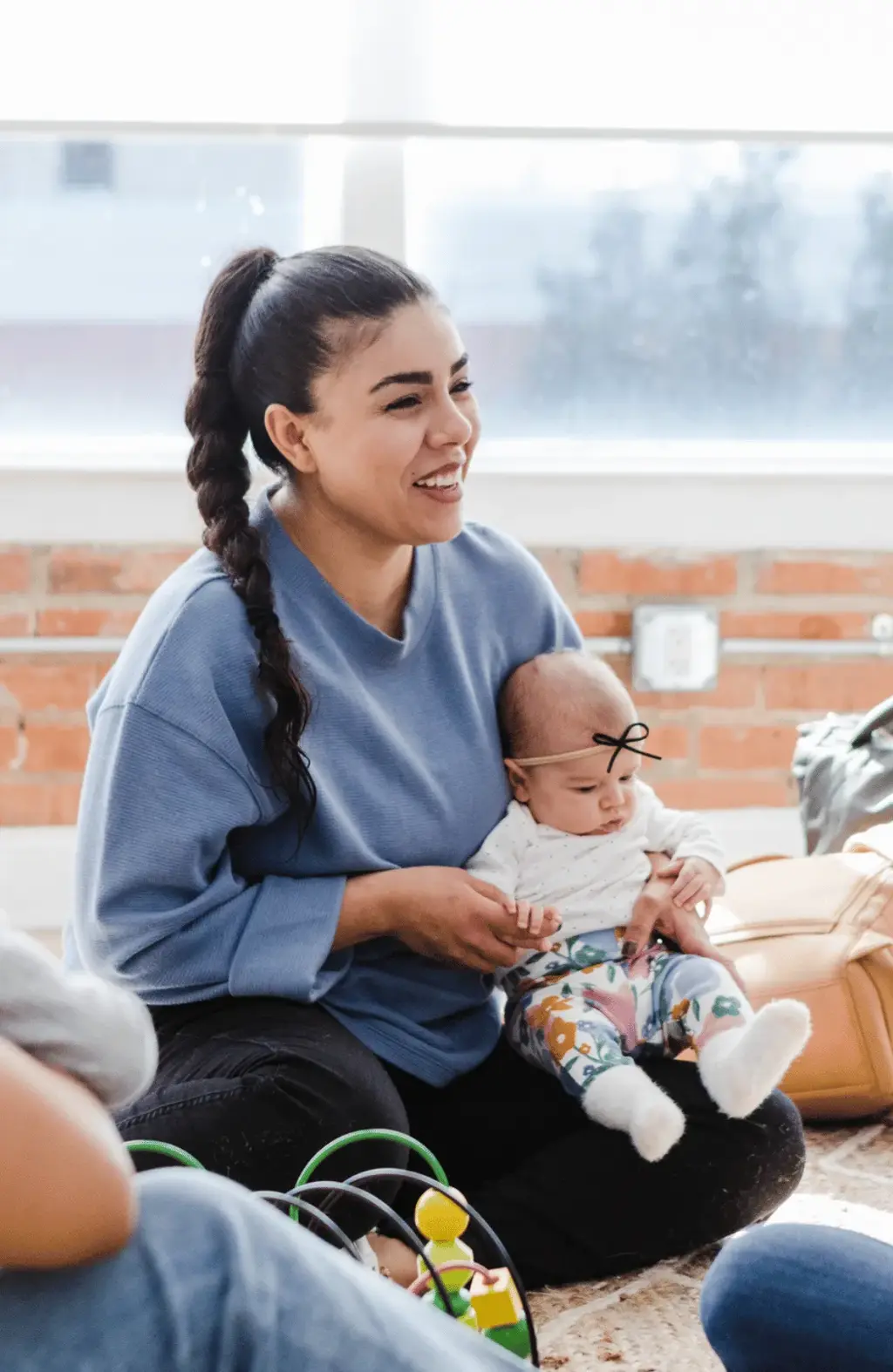 A mum smiling sitting with her baby on her lap talking things through with others