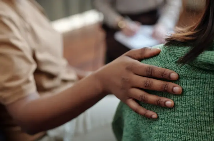 A therapist places a supportive hand on a person's back